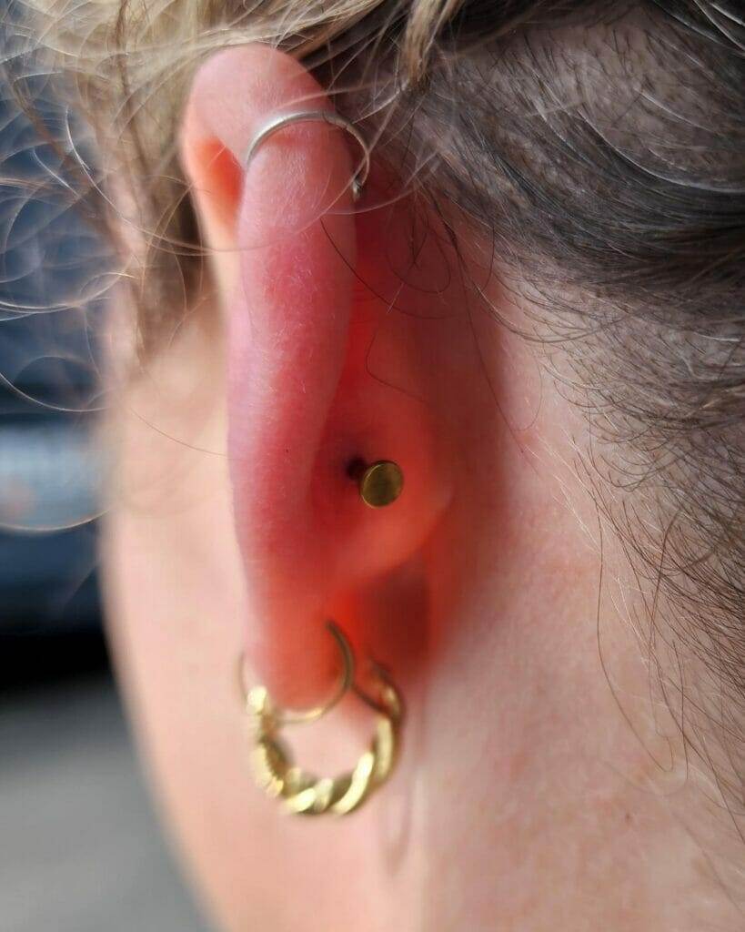 About a woman with a gold hoop ear piercing.