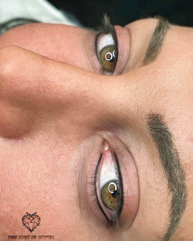 A woman's eye with a Dark Heart tattoo.