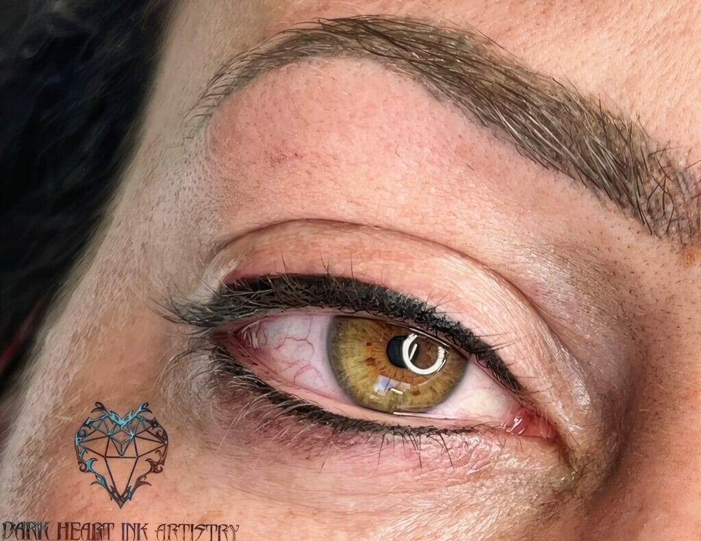 A close up of a woman's eye with dark eyebrows.