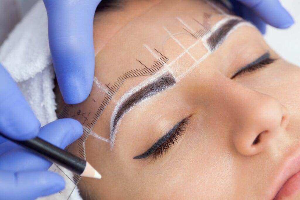 A woman getting her eyebrows microbladed at a beauty salon.