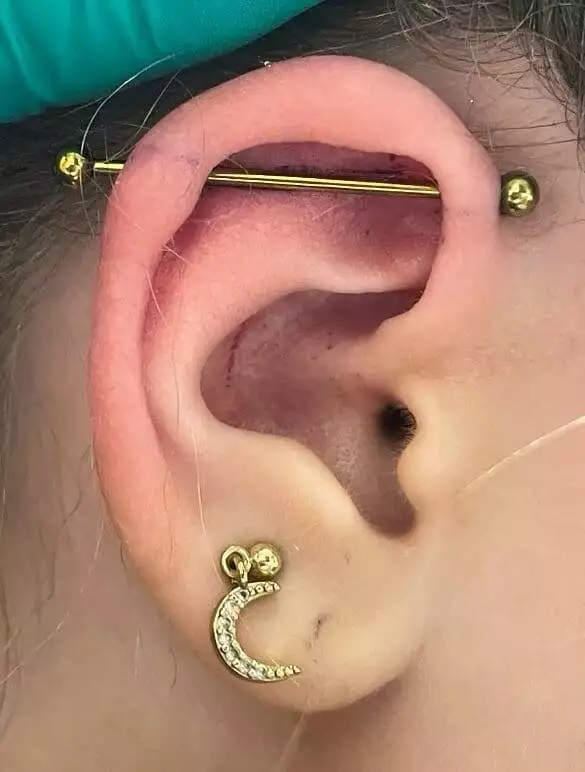 A woman's ear with a crescent piercing inspired by Eddie Kon.