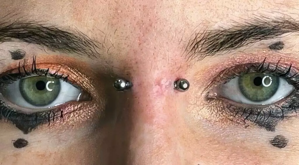 A close up of a woman's eyes with piercings named Ronnie Shaw.