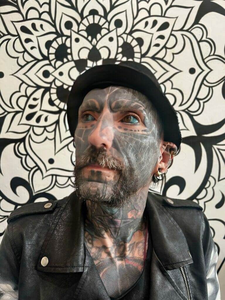 Ronnie Shaw: A man in a leather jacket with tattoos on his face.