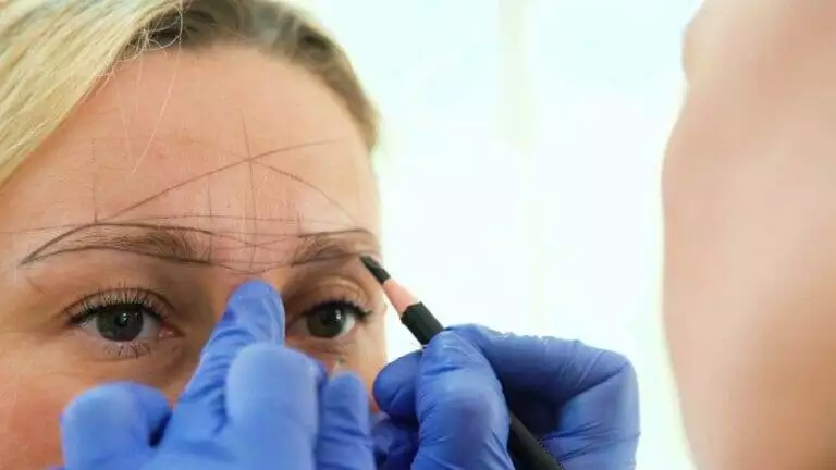 A woman is receiving microblading for her eyebrows.