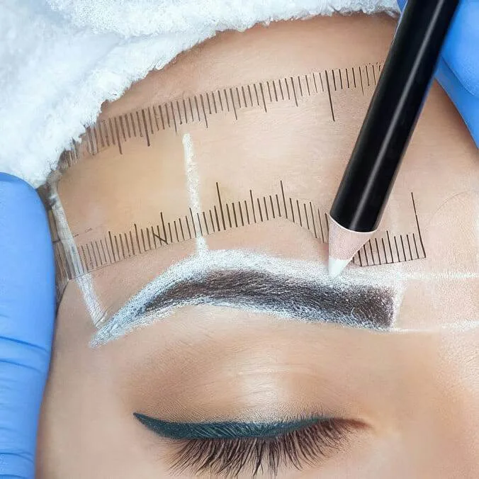 A woman is getting her eyebrows tattooed at home.