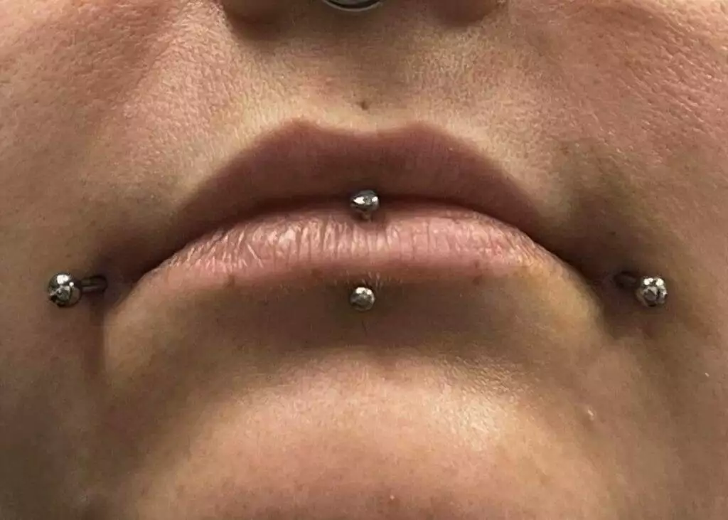 A woman offering lip piercing services.