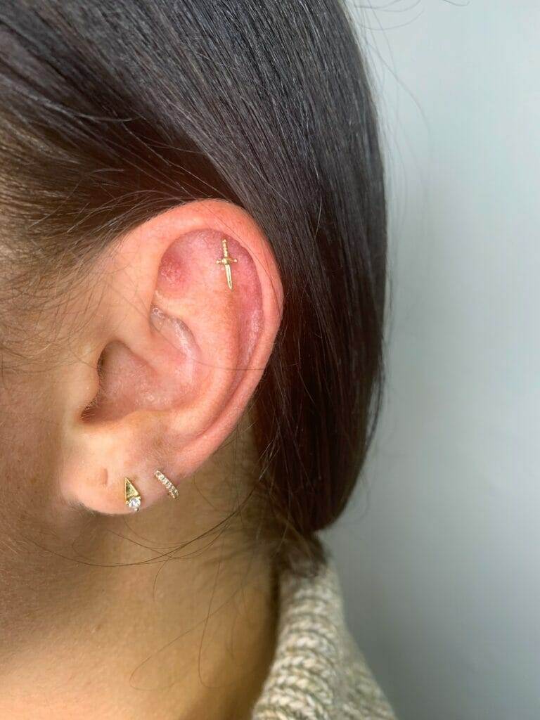 A woman's ear with a gold ear piercing, modified with the keyword "gold.