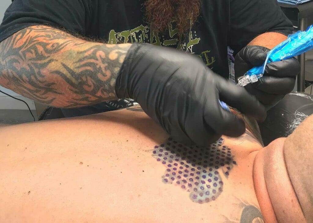 A man is receiving tattoo services on his chest.