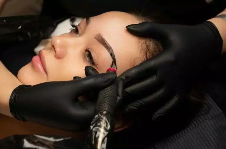 A woman getting her eyebrows tattooed at a salon.